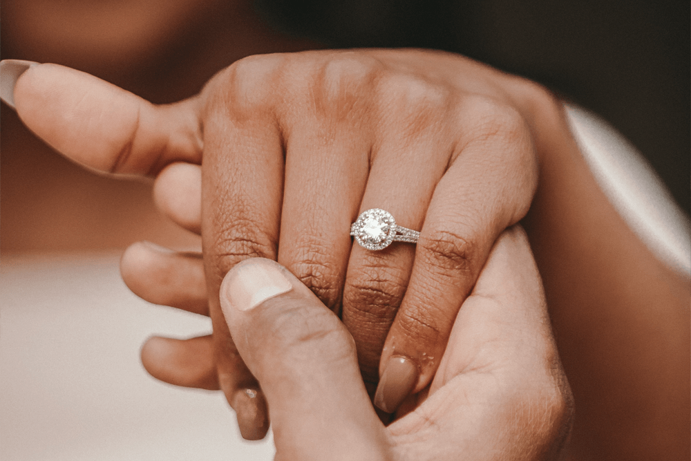 Close-up of a hand wearing a diamond engagement ring with a halo design